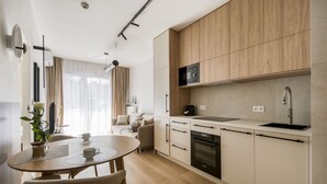 Eine moderne Küche mit Essbereich, Holzschränken, einer eingebauten Mikrowelle und einem Geschirrspüler.