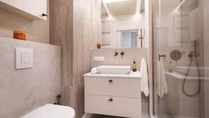 Ein modernes Badezimmer mit Toilette, Waschbecken und Duschbereich.