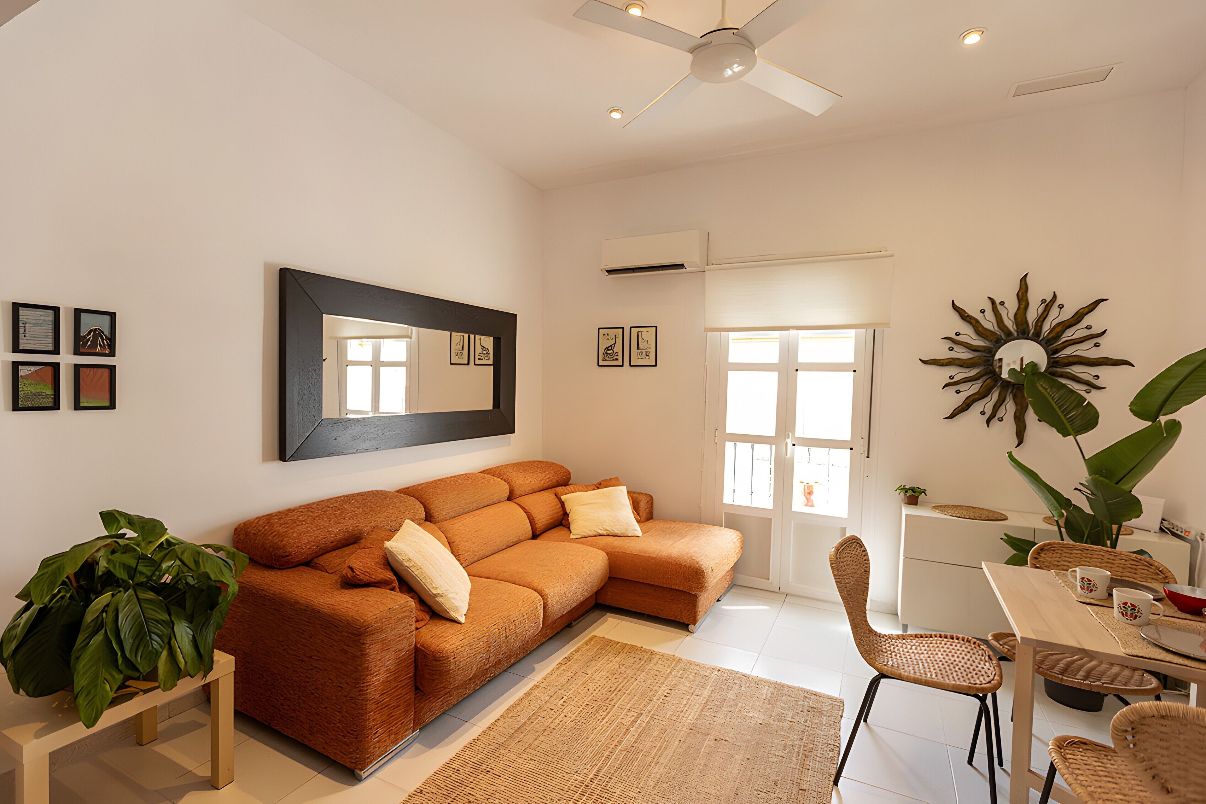 A modern living room with a sectional sofa, a dining table with chairs, and a large mirror on the wall.