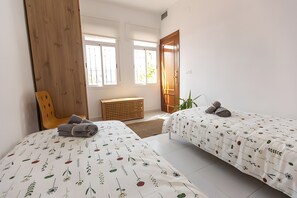 A bedroom with two beds, a wooden wardrobe, a window, and a door. - Holiday Home 'Impresonante Ático En El Centro' with Wi-Fi (Seville)