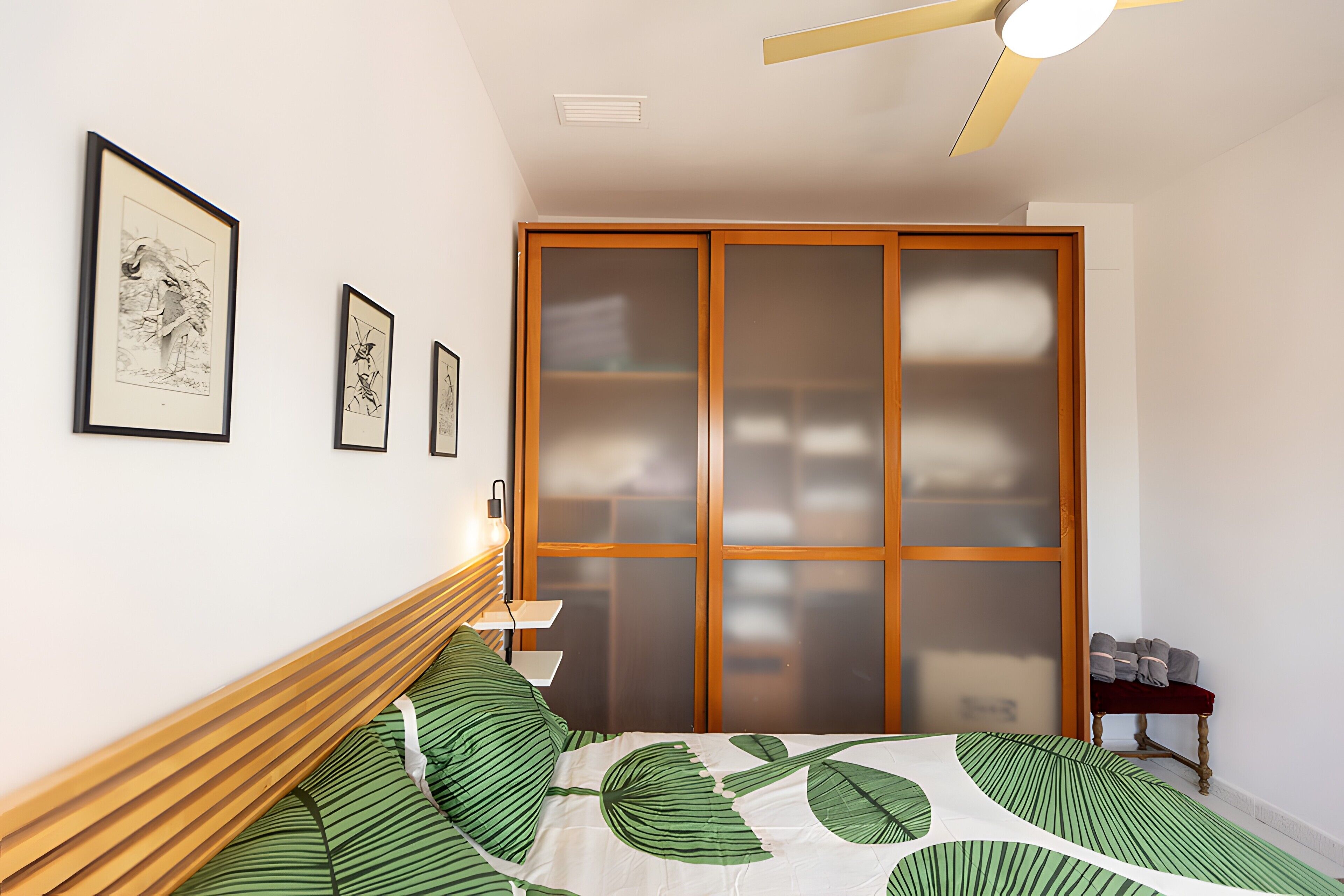 Ein Schlafzimmer mit Bett, Deckenventilator und Schiebetürenschrank.
