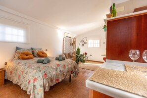 A bedroom with a bed, a bedside table, a hanging plant, and a window. - Ático Maravilla Sol – Bright Penthouse on 3rd Floor with Terrace (Seville)