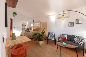 Ein modernes Wohnzimmer mit einer Couch, einem Esstisch und einem Stuhl. Auf dem Tisch steht ein Blumentopf, und ein weiterer steht auf dem Boden.