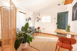 Ein modernes Wohnzimmer mit Sofa, Couchtisch, Zimmerpflanze und Essbereich mit Tisch und Stühlen.
