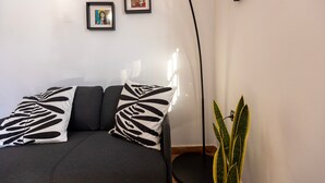 Habitació amb un sofà, dos quadres al mur i una planta en test.