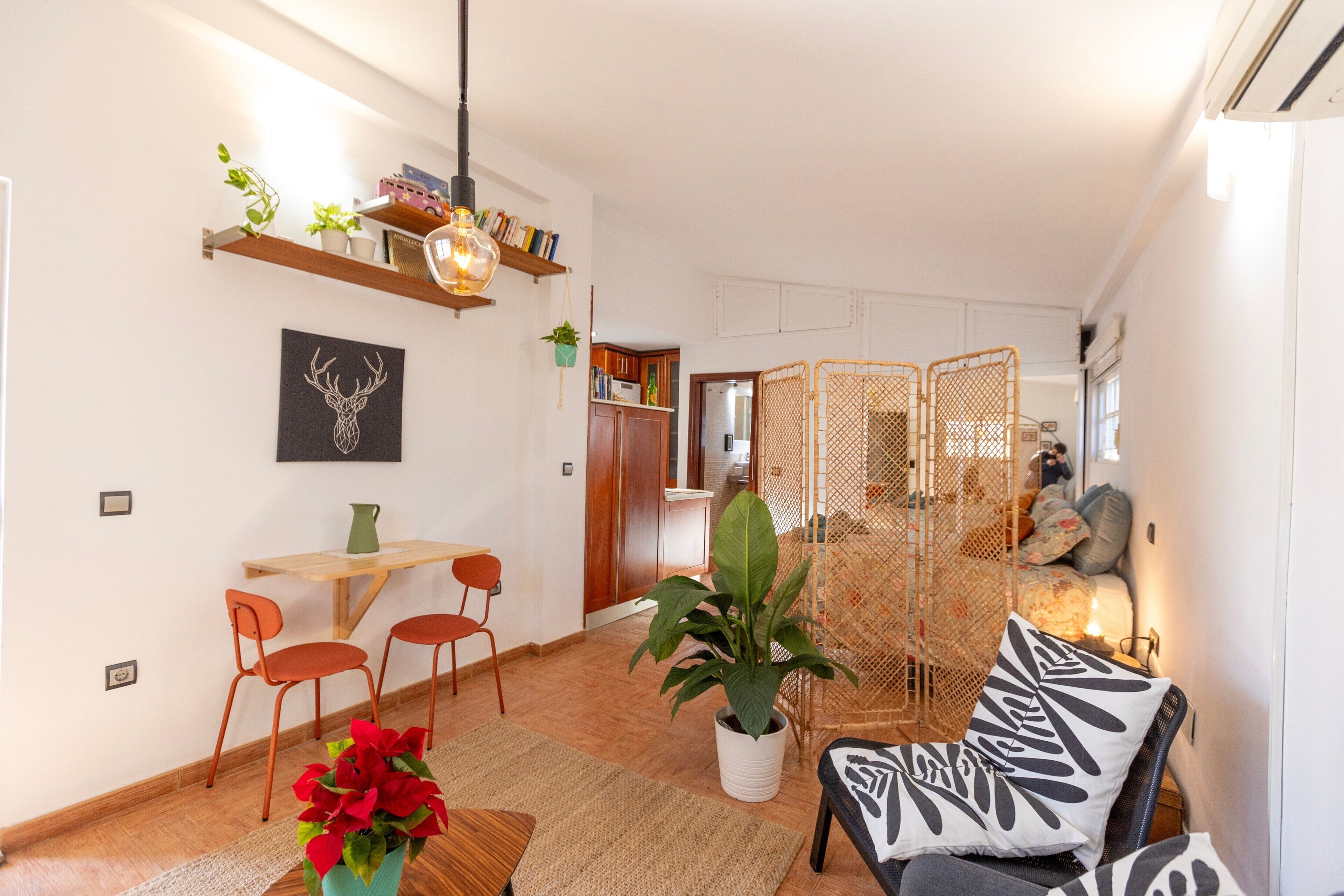 Un espacio de estar moderno con comedor, sofá y una planta decorativa.