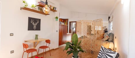 Un espacio de estar moderno con comedor, sofá y una planta decorativa.