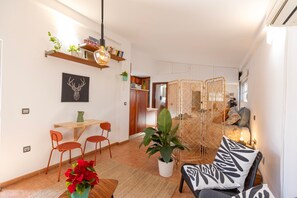 A modern living space with a dining area, a sofa, and a decorative plant. - Ático Maravilla Sol – Bright Penthouse on 3rd Floor with Terrace (Seville)