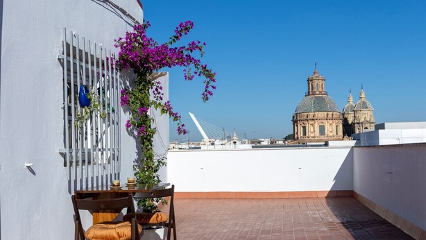 Una terrassa amb taula i cadires, un arranjament floral i vista d'un edifici històric.