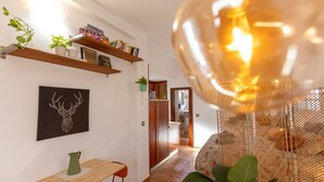 Un interior modern amb una taula de fusta, un vas verd i una estant amb llibres i plantes.