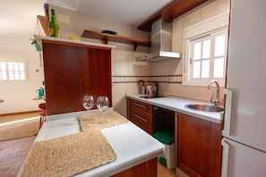 A kitchen with a white countertop, wooden cabinets, a stainless steel sink, and a window above the sink. - Ático Maravilla Sol – Bright Penthouse on 3rd Floor with Terrace (Seville)