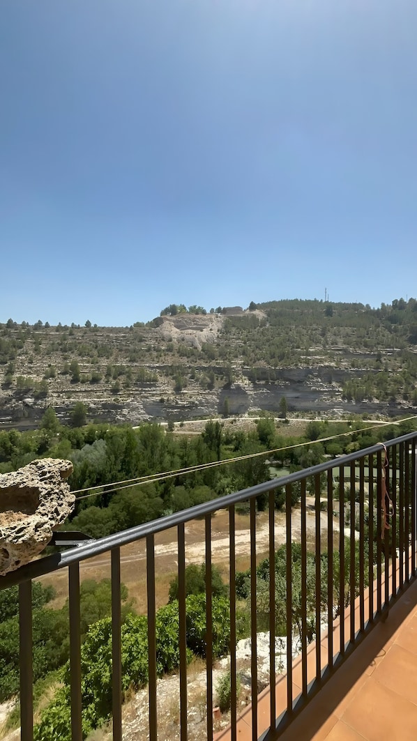 A balcony with a view of a rocky hillside and a river.