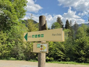 A directional signpost with multiple arrows and symbols indicating hiking trails and facilities. - Les Caribous - 5 min from Megève, Lake and Espace Diamant (Praz-sur-Arly)