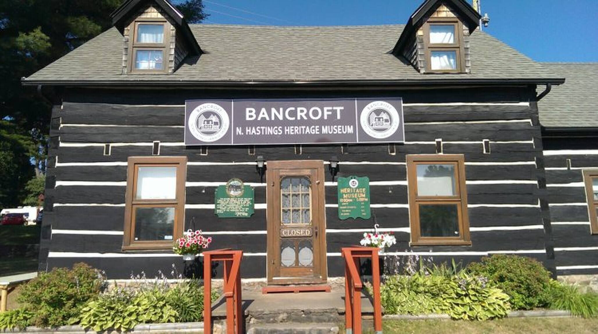 A log cabin with a sign for Bancroft N. Hastings Heritage Museum.