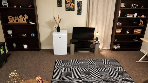A living room with a TV, a white refrigerator, and a bookshelf.