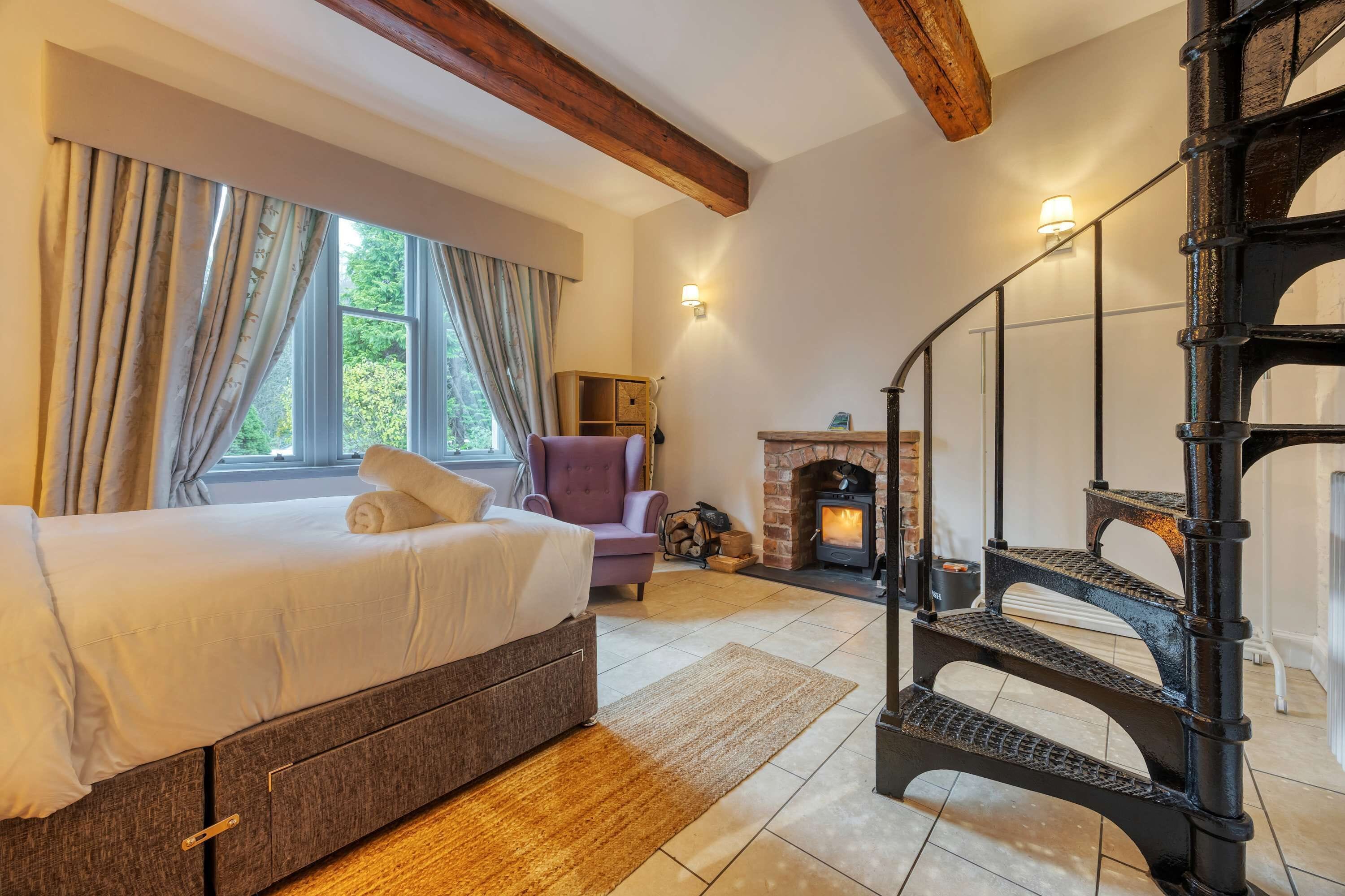 Une chambre à coucher avec un lit, une chaise, une cheminée et un escalier.