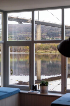 A room with a large window overlooking a river and a bridge.