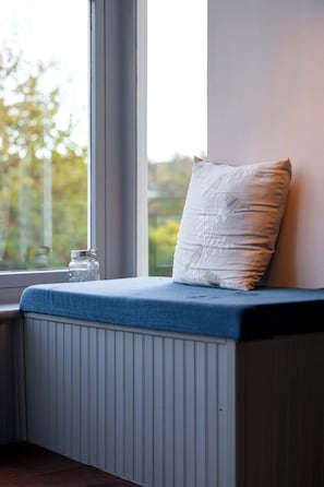A window seat with a cushion and a small table with a glass jar. - Riverside Retreat with Private Beach (Erskine)