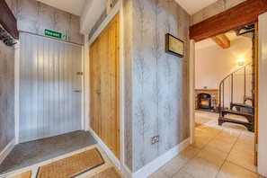 A hallway with a fire exit sign, a wooden door, and a fireplace in the background. - Riverside Retreat with Private Beach (Erskine)