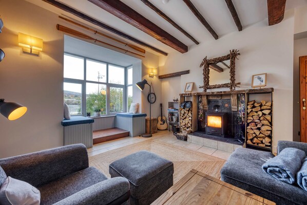 A cozy living room with a fireplace, seating area, and large windows.