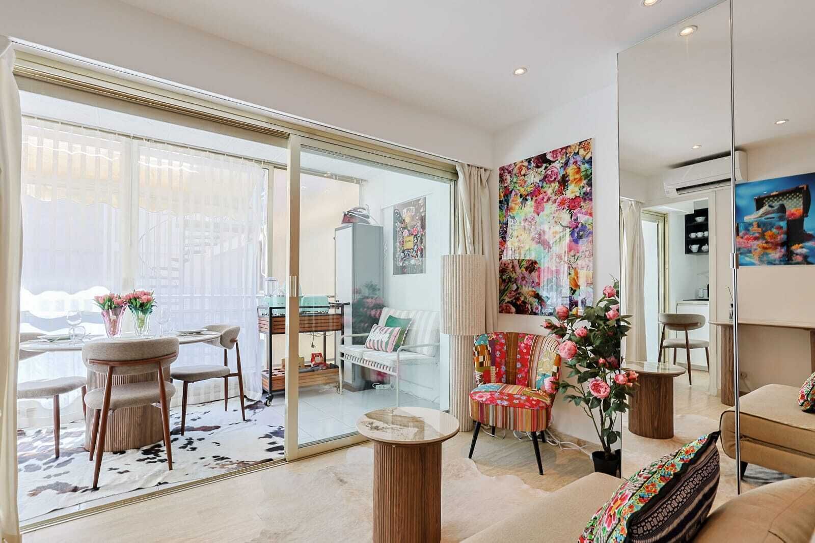 Un salon moderne doté d’une porte vitrée donnant sur un balcon, d’un canapé, d’une table basse et d’un fauteuil à motifs.