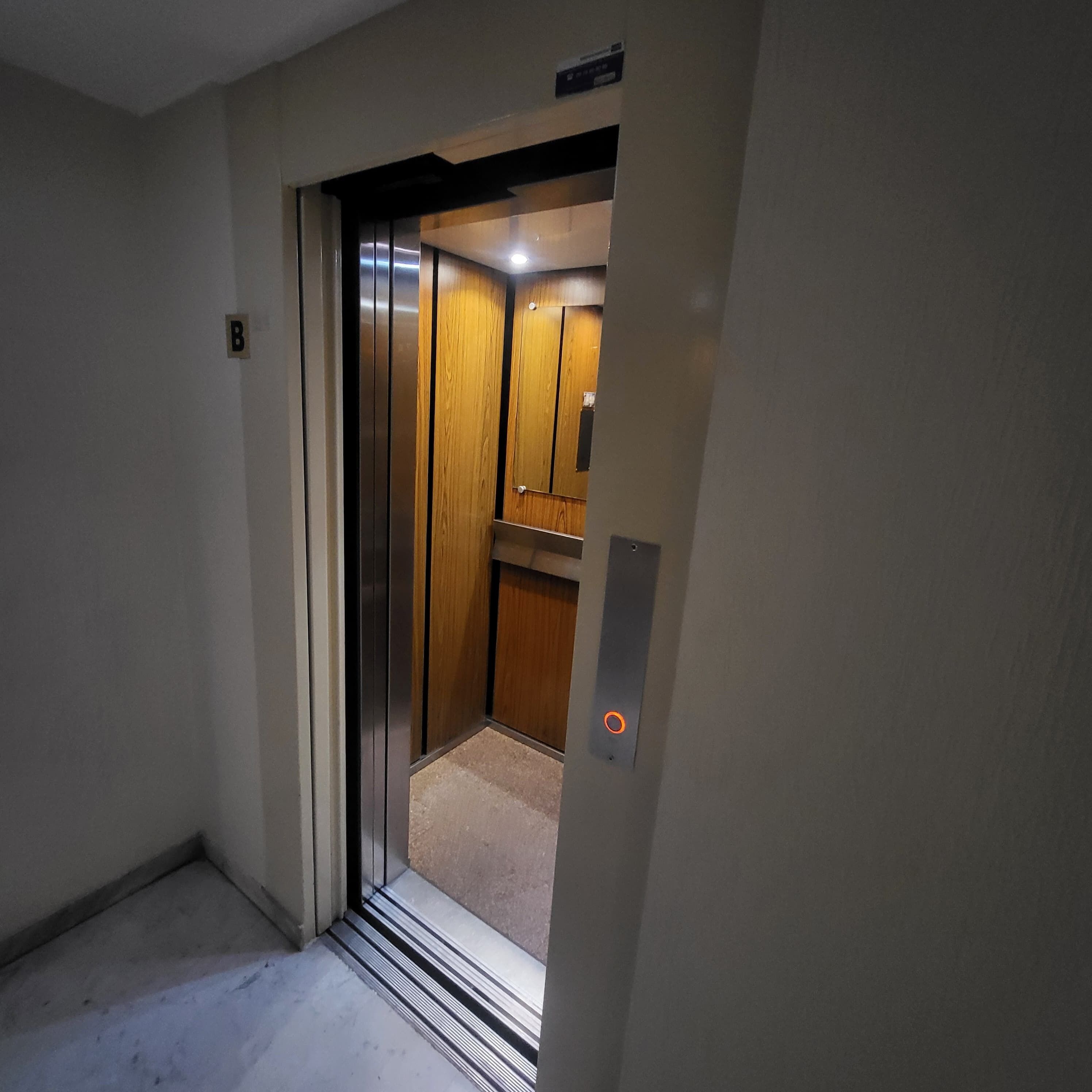 An elevator with a wooden interior and a metallic door.