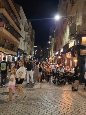 A bustling street scene at night with people walking and dining outdoors. - 140m from the Palace of Festivals #Croisette #city center #air conditioning #Wi-Fi #elevator #terrace (Cannes)