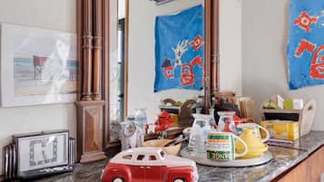 A cluttered room with a vintage car model, a clock, and various items on a counter.