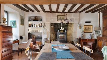 A traditional room with a wooden table, chairs, a fireplace, and various decorative items.