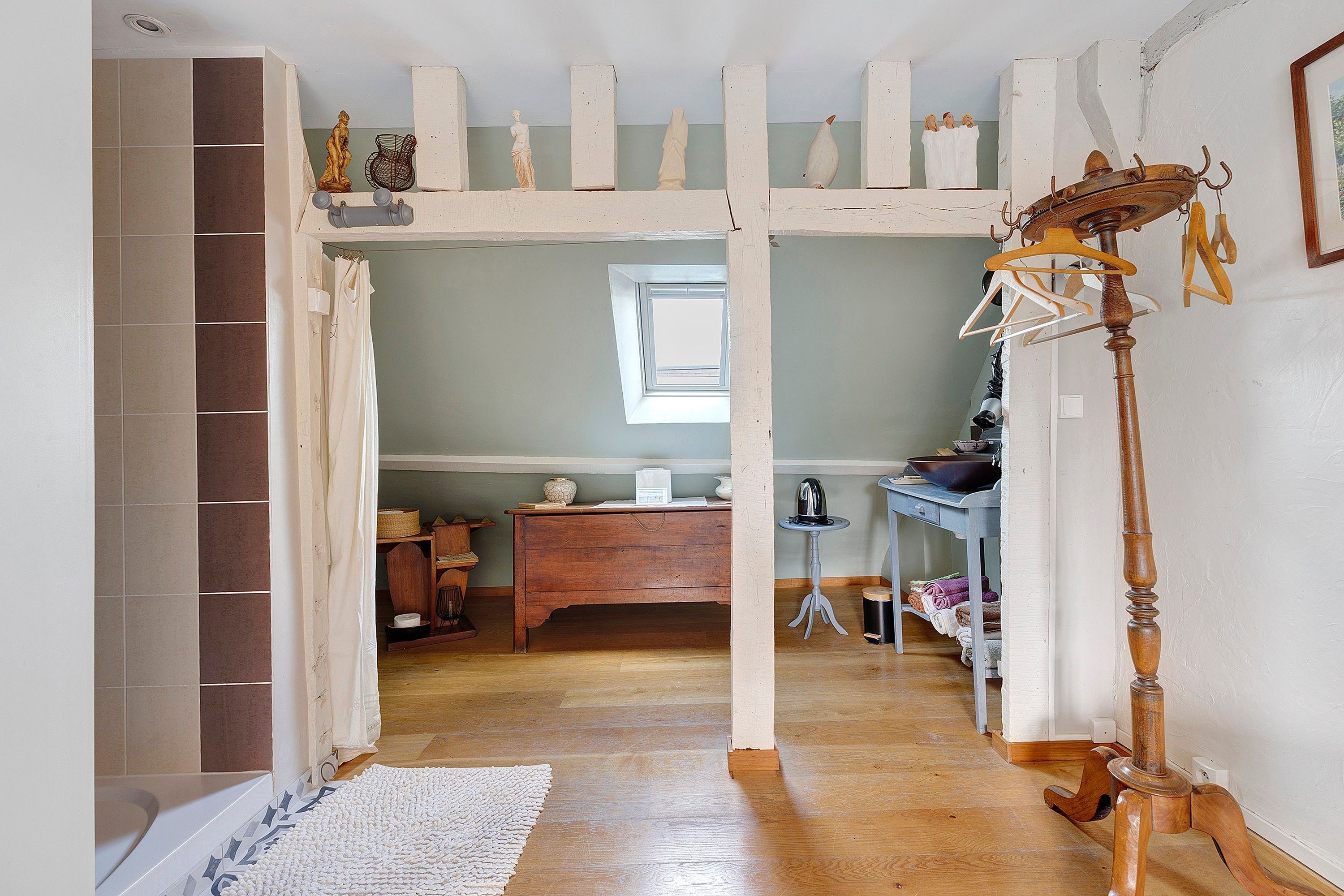 Une pièce avec un plancher en bois, un bureau orné d’un vase, une lampe suspendue et une fenêtre donnant sur un beau paysage.