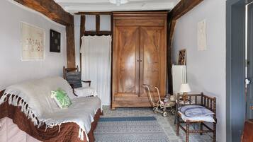 A room with a bed, a chair, a wooden wardrobe, a radiator, and a wall with pictures.