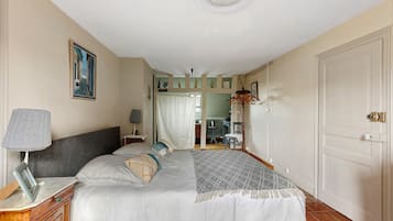 Une chambre à coucher avec un lit, des tables de chevet, une lampe, un tableau et une porte.