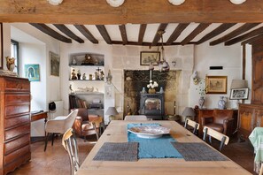 A traditional room with a wooden table, chairs, a fireplace, and various decorative items.