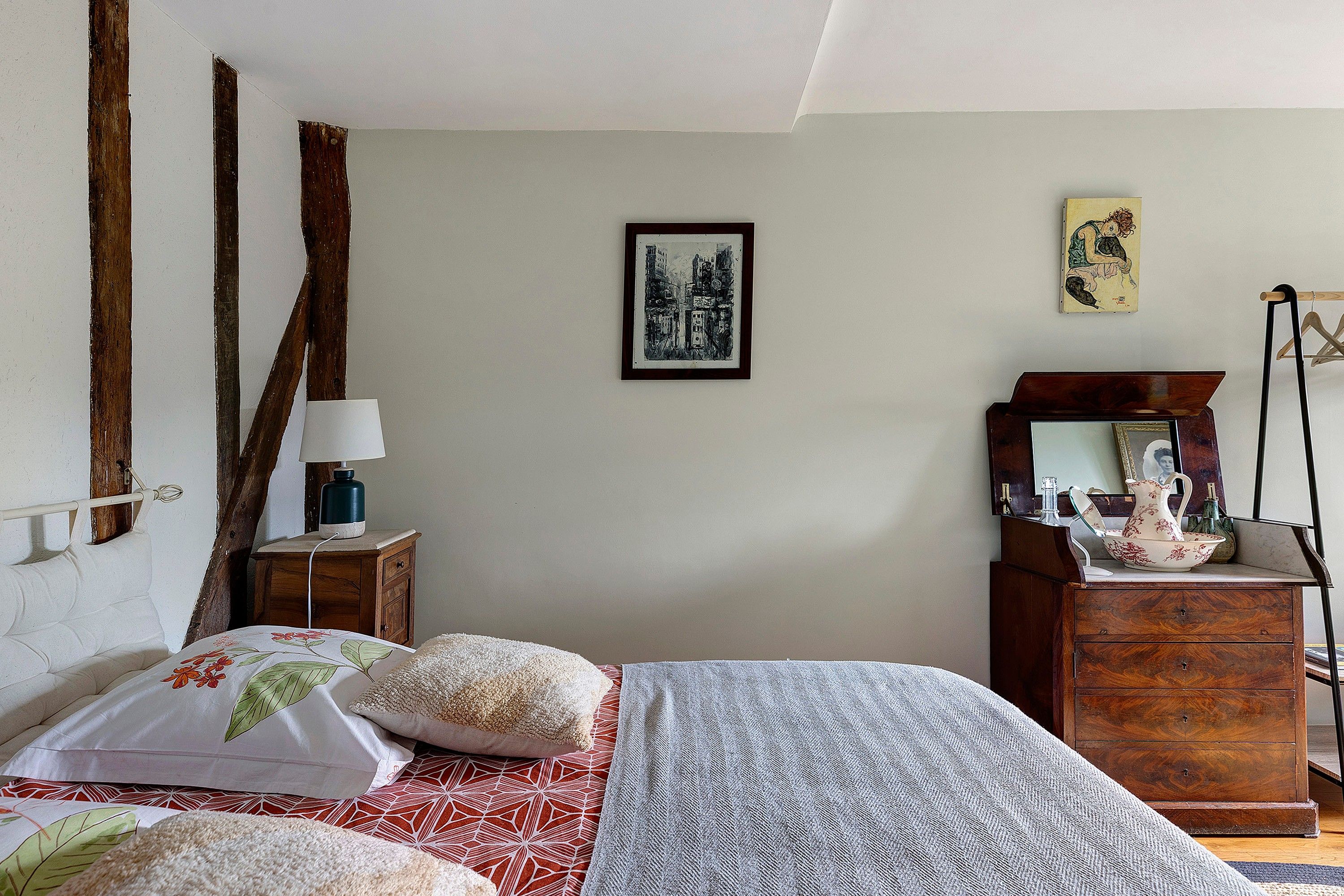 A bedroom with a bed, a dresser, a nightstand, a lamp, and a framed picture on the wall.