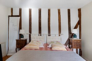 Un dormitorio con cama, dos mesitas de noche, una mesita auxiliar y un cabecero de madera, además de una pizarra blanca.