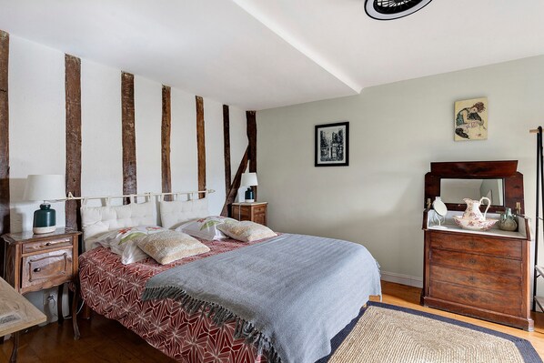 A bedroom with a bed, bedside tables, a dresser, a mirror, and artwork on the wall.