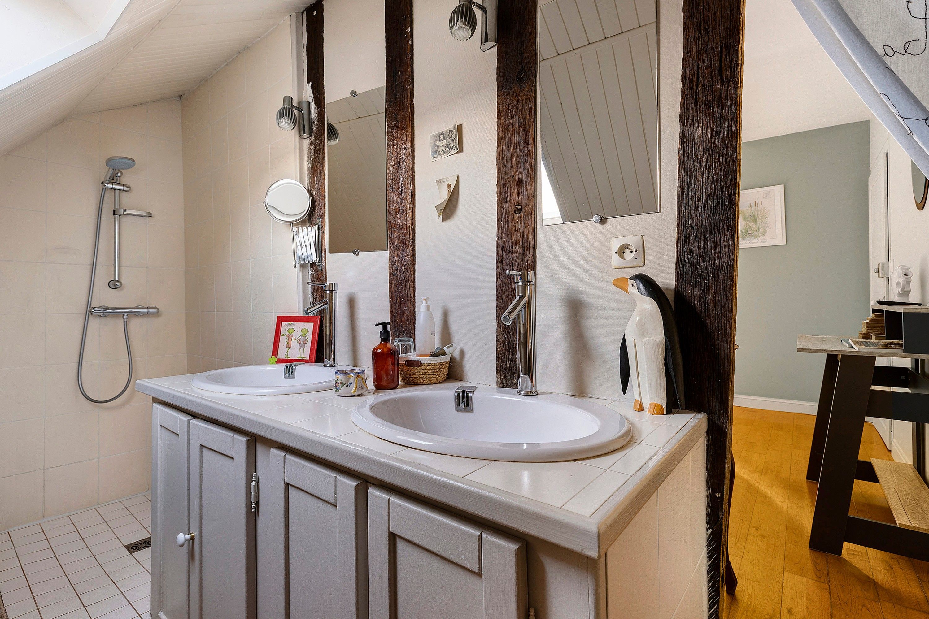 Een badkamer met twee wastafels, een douche en een spiegel.
