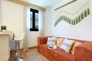 A compact living space with a sofa, a small table, a chair, and a wall-mounted decorative piece.