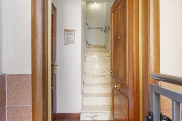 A staircase leading to a landing with a wooden door on the right and a sign on the wall.
