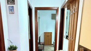 A hallway with a wooden bench, a small plant, and a door with a mirror. - Family House San Marco – A Warm Welcome Near Taormina and Mount Etna. (Calatabiano)
