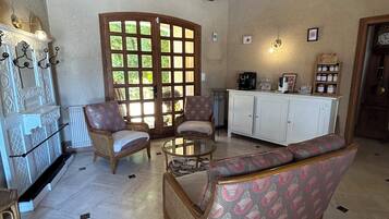 A spacious room with a high ceiling, wooden beams, a large window, and a seating area with a sofa and chairs.