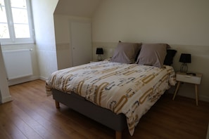 A bedroom with a bed, two bedside tables, a window, and a radiator. - GRAND GITE LA MONERIE, for your stays with family, friends, or for business (Segré-en-Anjou Bleu)
