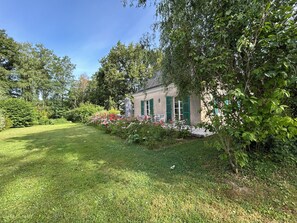 A building with a garden, a lawn, and a tree.