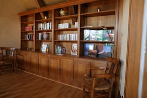 A wooden bookshelf filled with books and magazines, a globe, and a lamp.