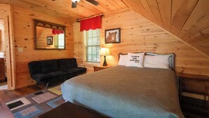 A cozy bedroom with a wooden ceiling, a bed with a green bedspread, a black sofa, a window with blinds, and a ceiling fan. - Firepit, hot tub, sleeps 7, exclusive hiking for resort, volleyball, peaceful! (Sevierville)