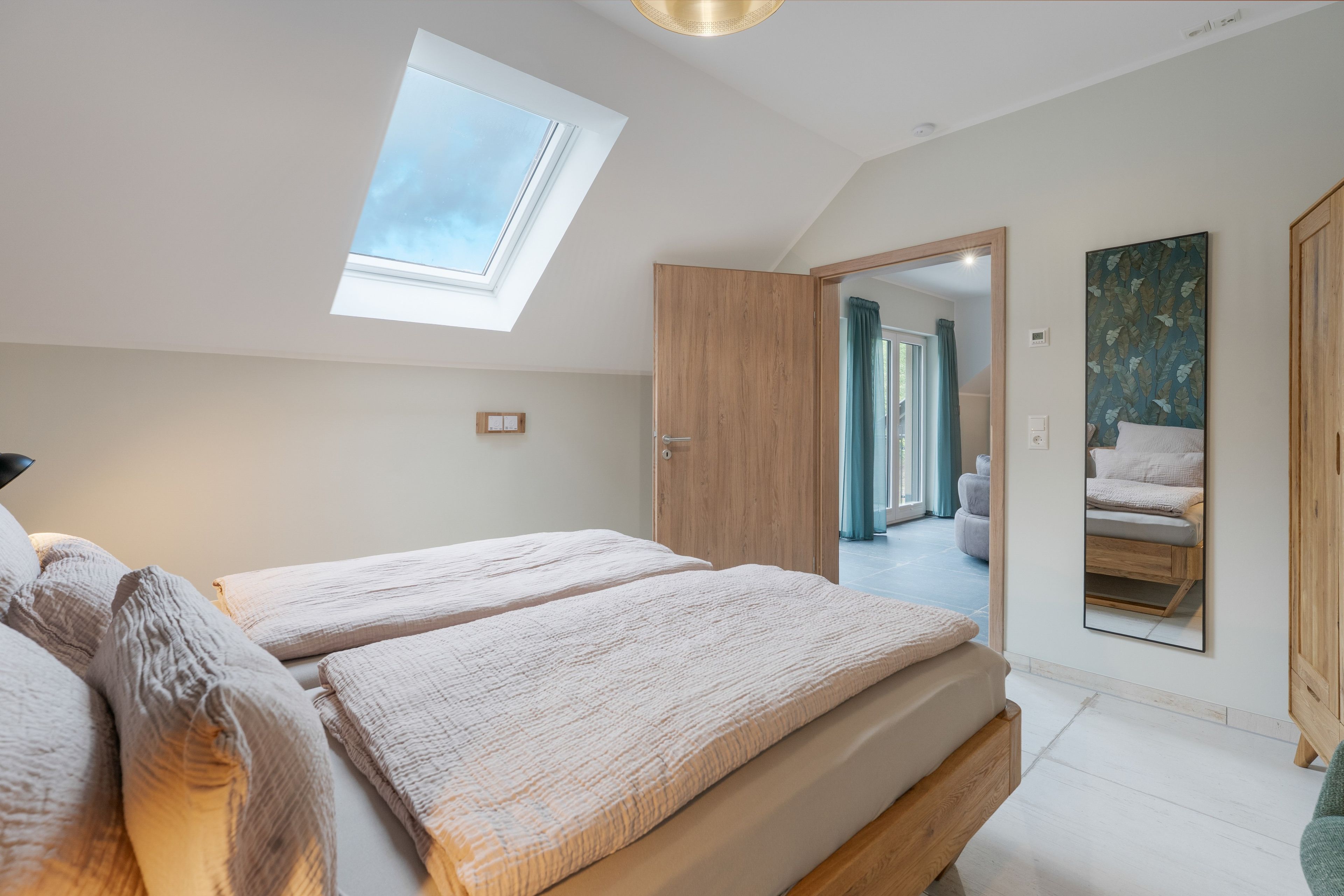 Ein Schlafzimmer mit Oberlicht, einem Bett, einem Kleiderschrank und einem Spiegel.