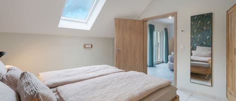 A bedroom with a skylight, a bed, a wardrobe, and a mirror.