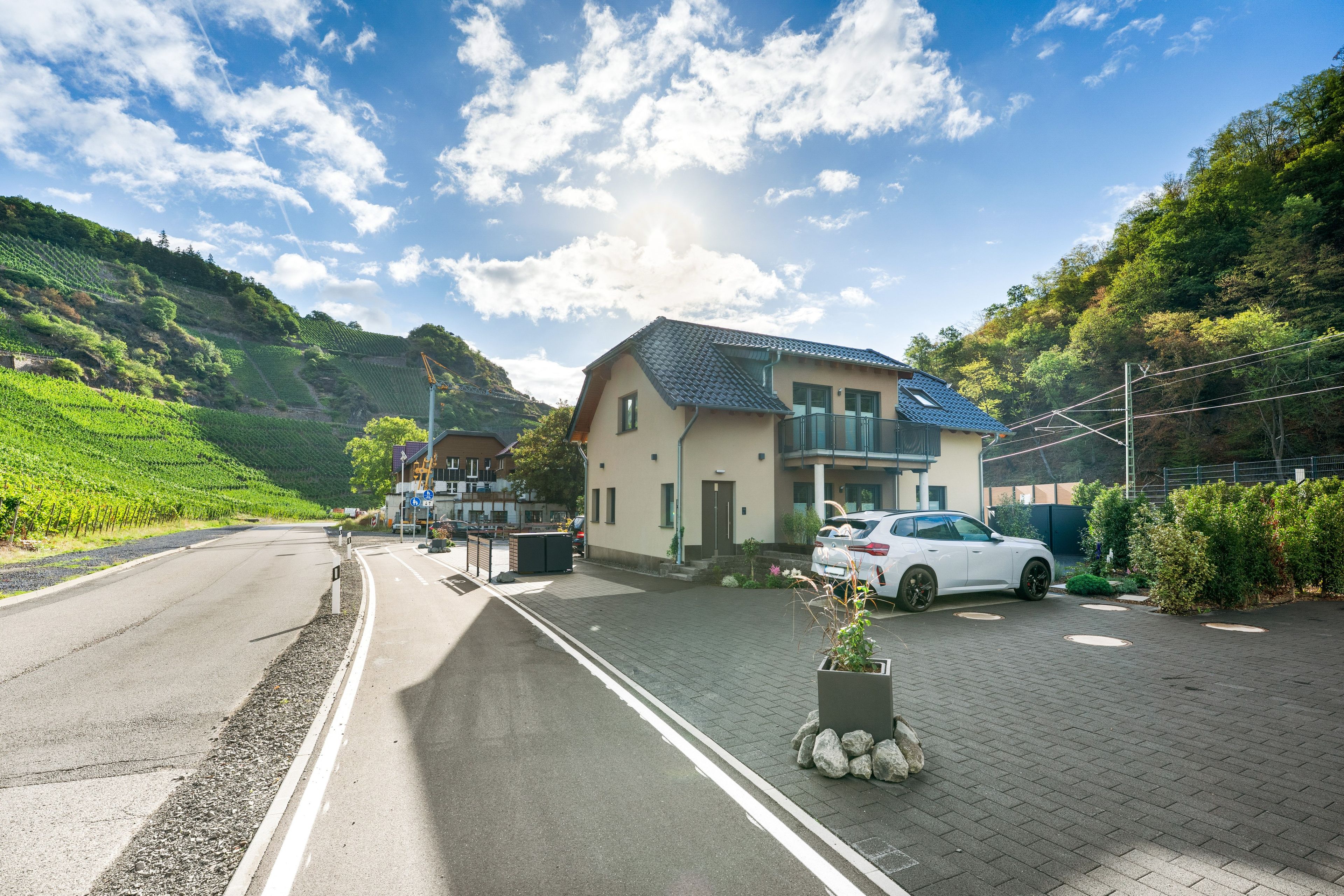 Een woonwijk met een huis, een geparkeerde auto en een weg.
