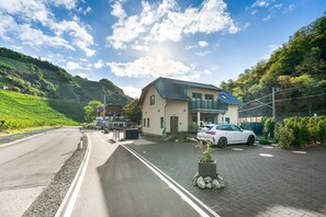 A residential area with a house, a parked car, and a road.