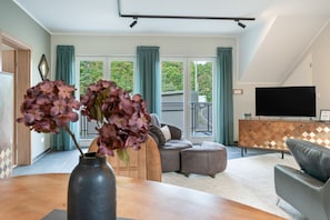 Ein modernes Wohnzimmer mit einer Couch, einem Fernseher und einer Vase mit Blumen.